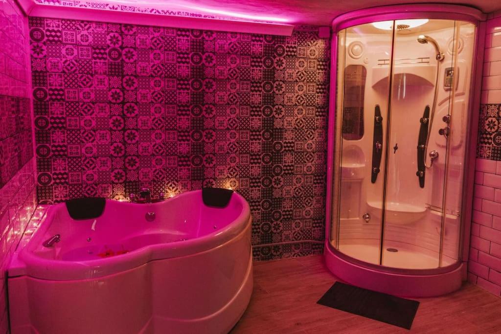 un bagno rosa con vasca e doccia di BONITA CASA CUEVA CON JACUZZI a Paterna