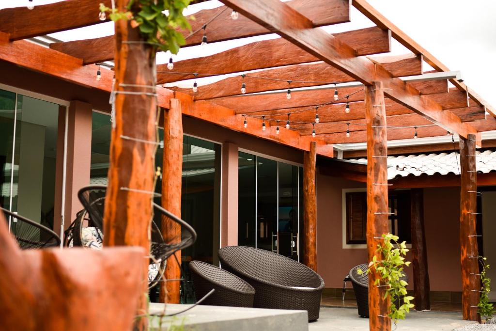 a wooden pergola with chairs on a patio at Lukinhas Pousada in Nobres