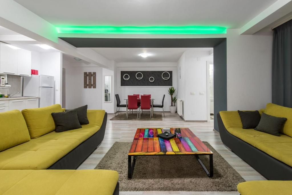 ein Wohnzimmer mit einem gelben Sofa und einem Tisch in der Unterkunft CityScape Bucharest in Bukarest