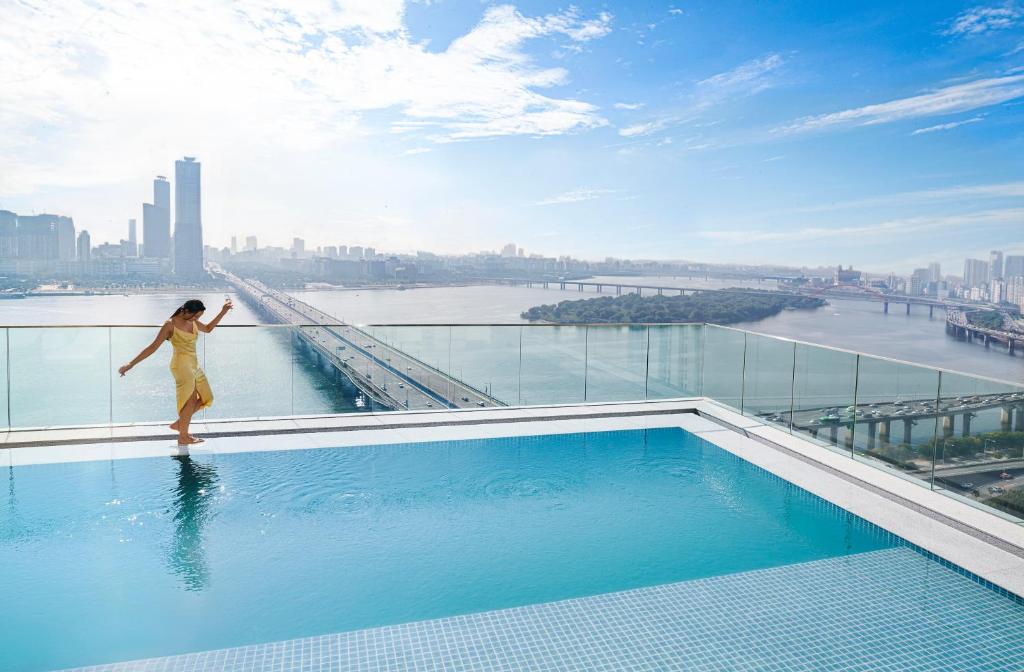 a woman standing on the edge of a swimming pool on a building at Hotel Naru Seoul MGallery Ambassador in Seoul