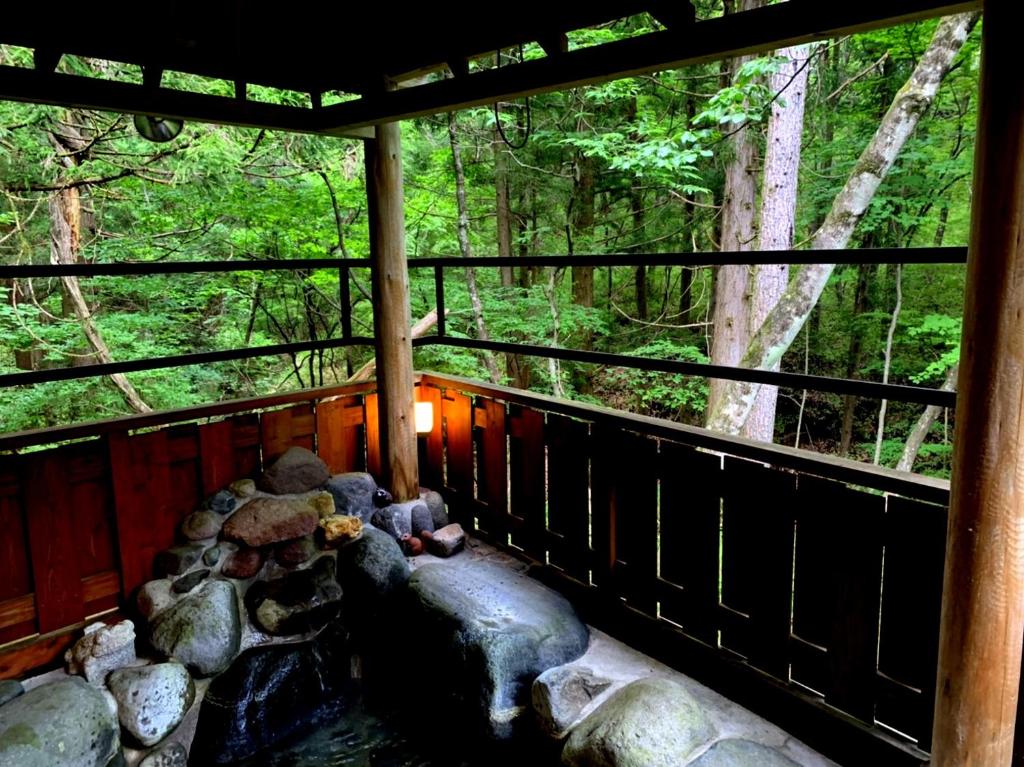 un porche de una cabaña con rocas y árboles en 一棟貸切 森のお風呂とアウトドアサウナ 日光雪月花, en Nikko
