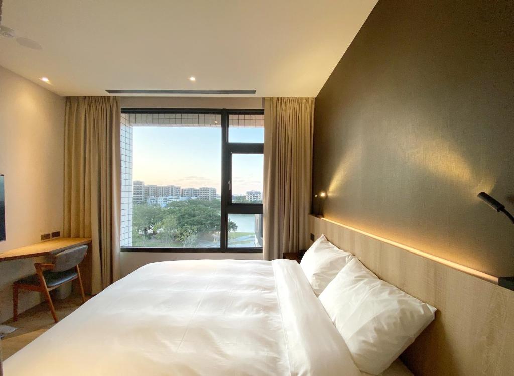 a bedroom with a large bed with a large window at alfar Hotel in Dayuan