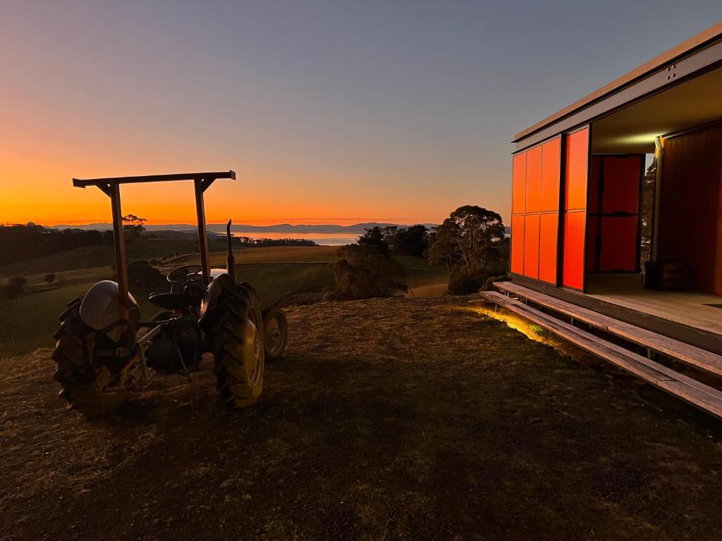 een tractor geparkeerd naast een gebouw met de zonsondergang op de achtergrond bij The Orange House in Premaydena