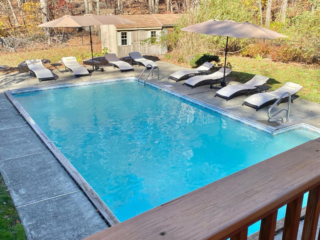 a swimming pool with chairs and an umbrella at Cedar Mill Hideaway in Woodbury