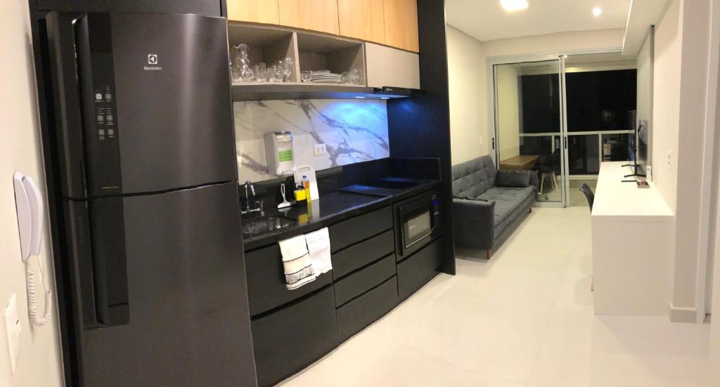 a kitchen with a black refrigerator and a living room at Monte Fuji ~ GRU 39m2 in Guarulhos