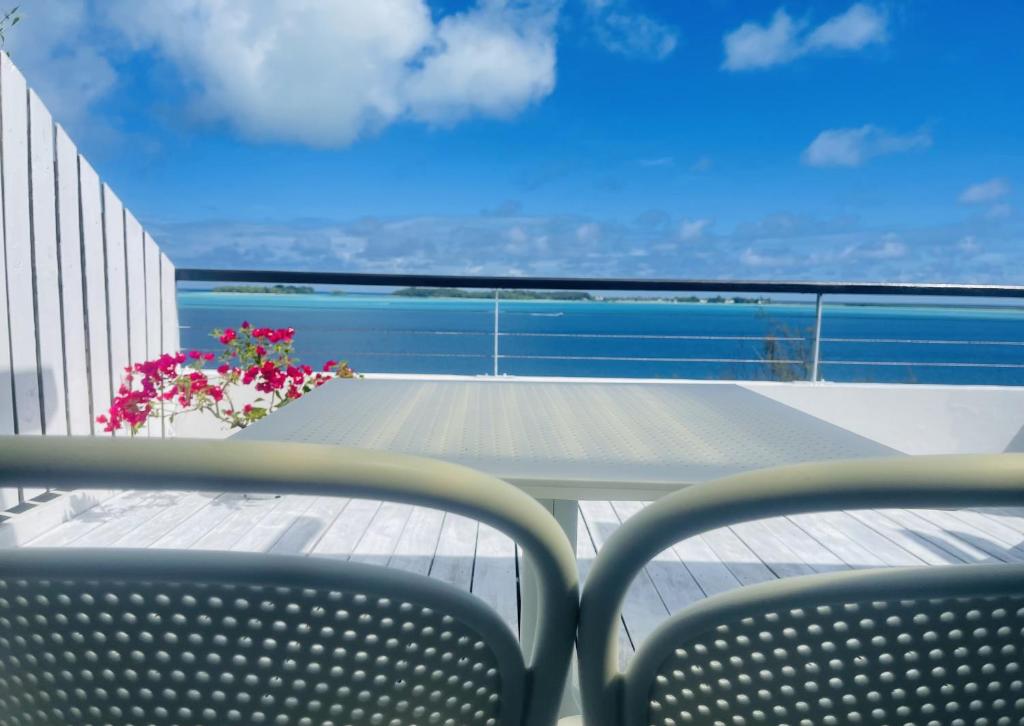 - un balcon avec 2 chaises, une table et des fleurs dans l'établissement Studio Deluxe, à Bora Bora