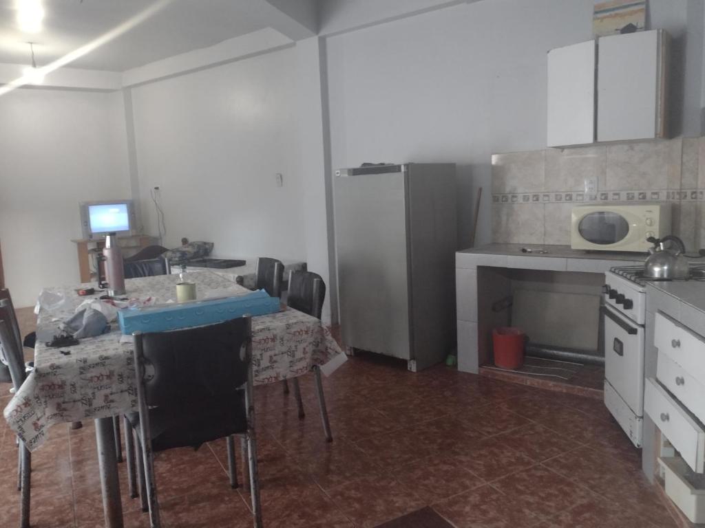 cocina con mesa, fogones y nevera en El descanso en Santa Teresita