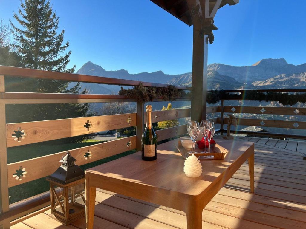 a wooden deck with a table with a bottle of wine at Chalet Crest-Voland, 7 pièces, 8 personnes - FR-1-505-181 in Crest-Voland