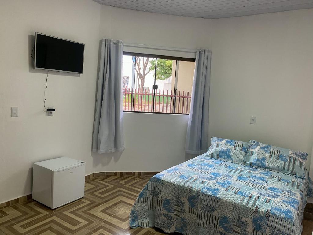 a bedroom with a bed and a television on the wall at Residencial da Praça in Bonito