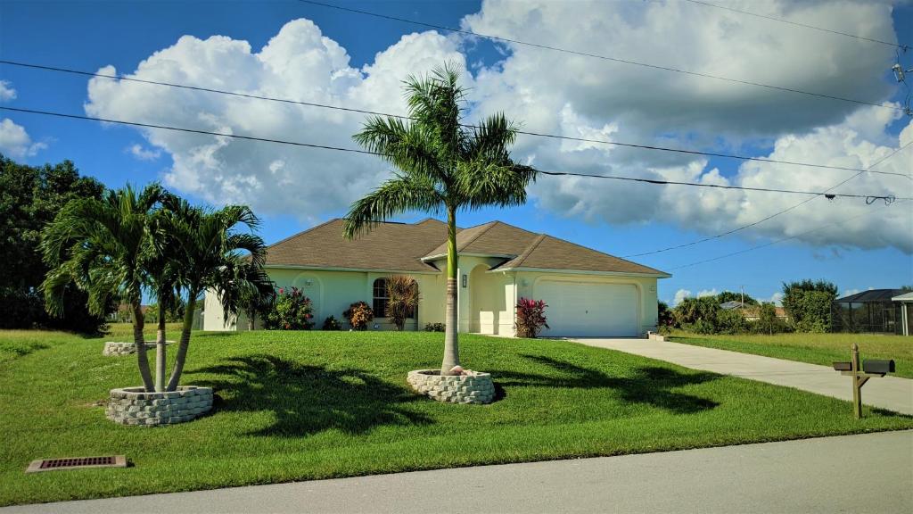 a house with two palm trees in the front yard at Villa Luhna 3 Bed / 2 Bath Canalfront Heated Pool in Cape Coral
