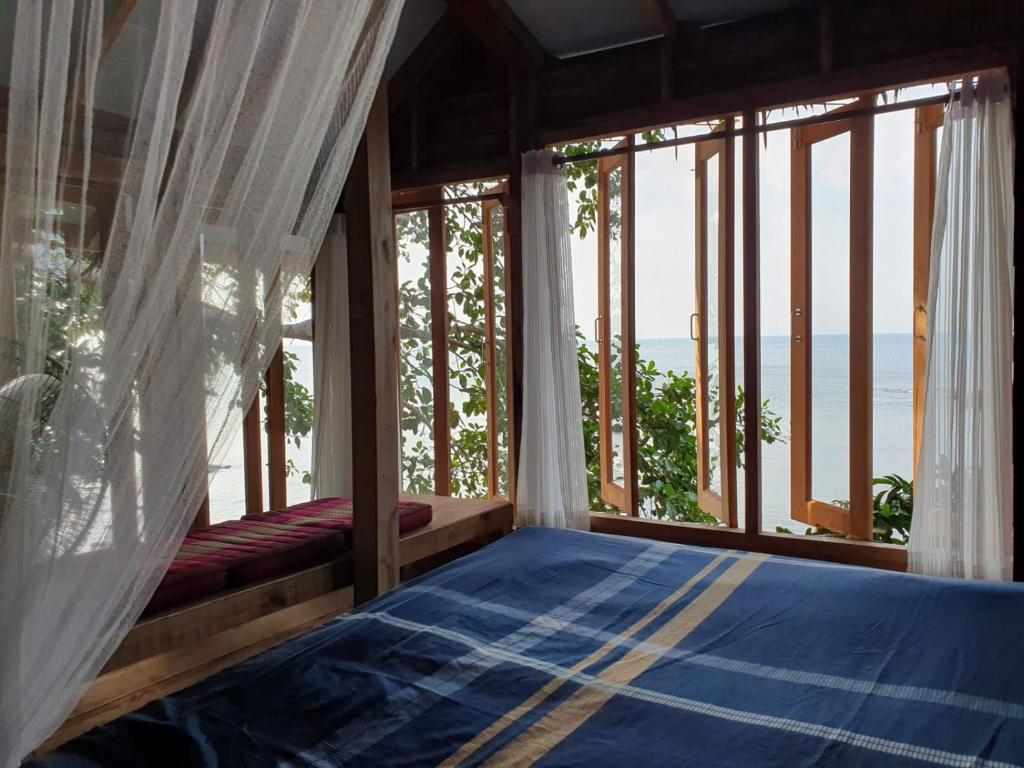 a bedroom with a bed with a view of the ocean at Palm Beach Resort Koh Phayam in Ko Phayam