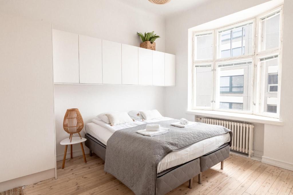a white bedroom with a bed and a window at 2ndhomes Mikonkatu Apartment 4 in Helsinki