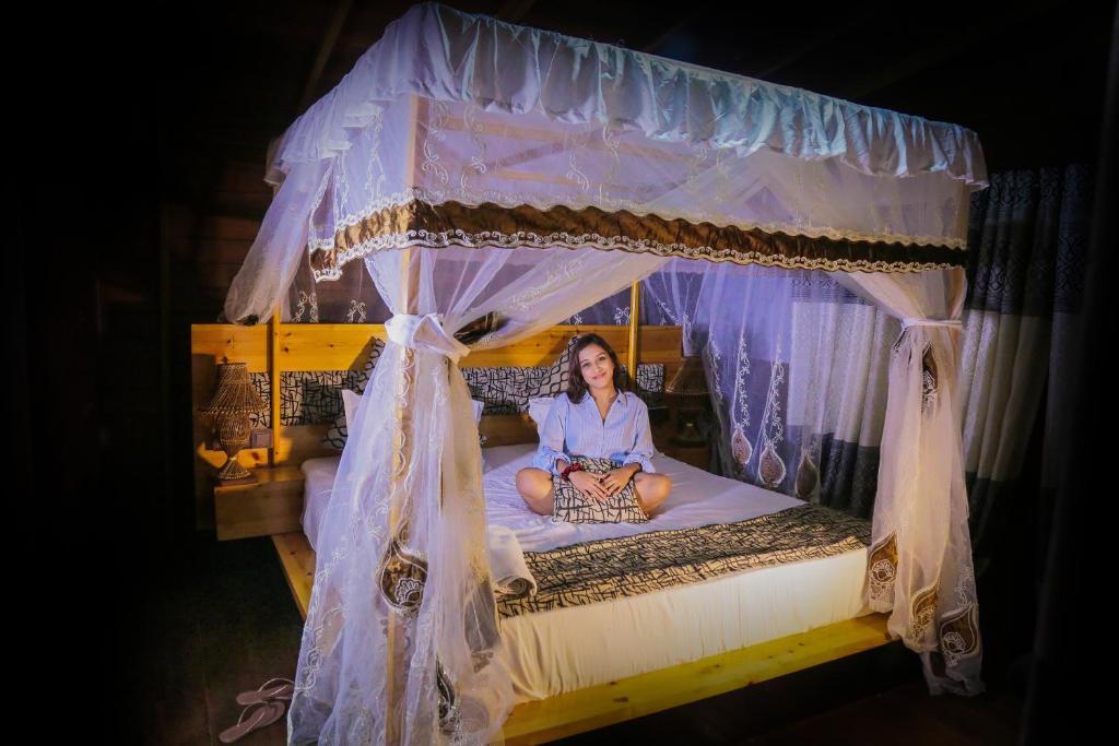 a woman sitting on a bed with a canopy at Leopard Nest - Glamping in Yala in Yala