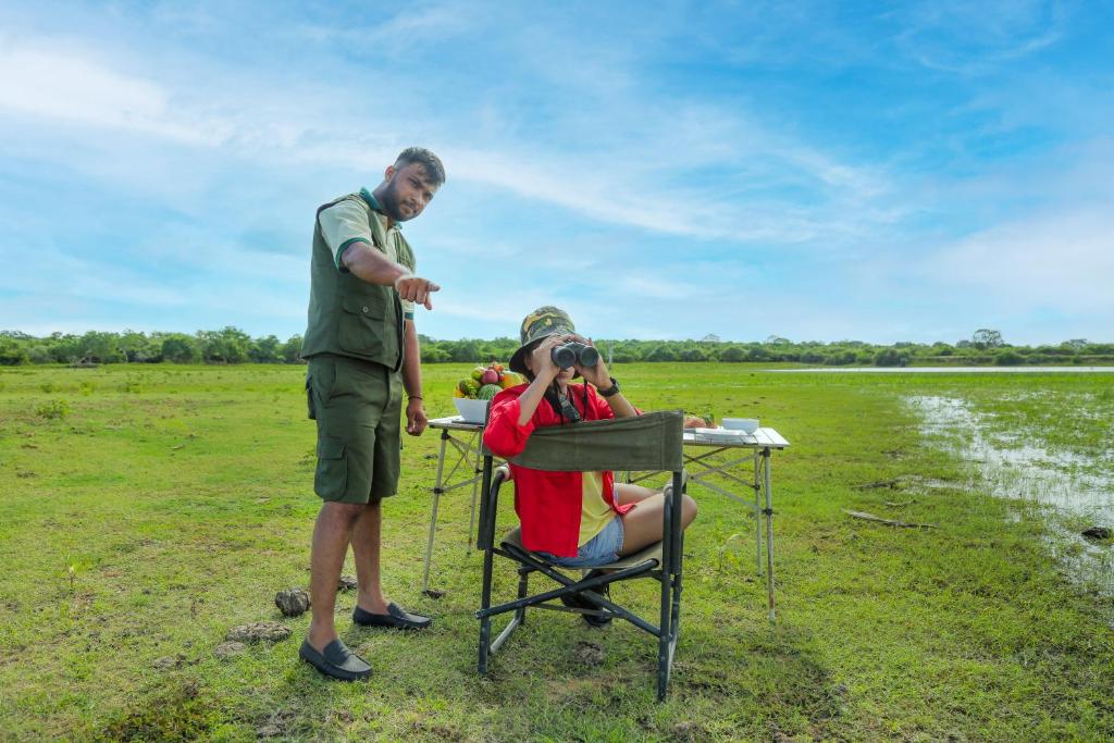 a man taking a picture of a woman sitting at a table at Leopard Nest - Glamping in Yala in Yala
