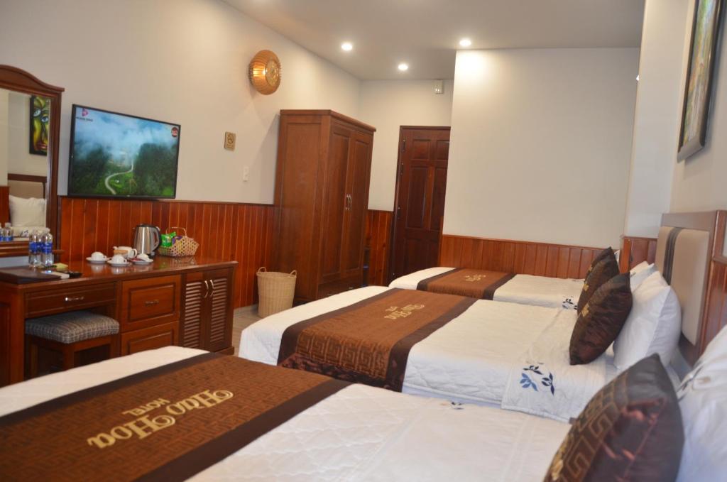 Habitación de hotel con 3 camas y escritorio. en Hào Hoa Hotel Kon Tum, en Kon Tum