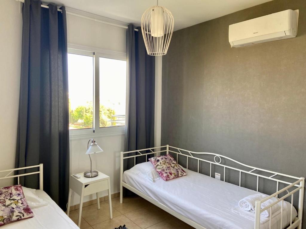 Habitación pequeña con 2 camas y ventana en Mythical Sands Resort - Antonios, en Paralimni