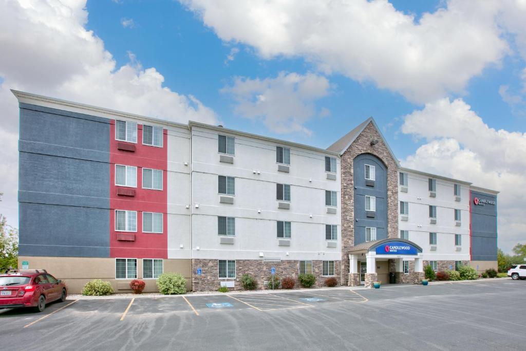 ein Hotel mit einem roten und weißen Gebäude neben einem Parkplatz in der Unterkunft Candlewood Suites Idaho Falls, an IHG Hotel in Idaho Falls