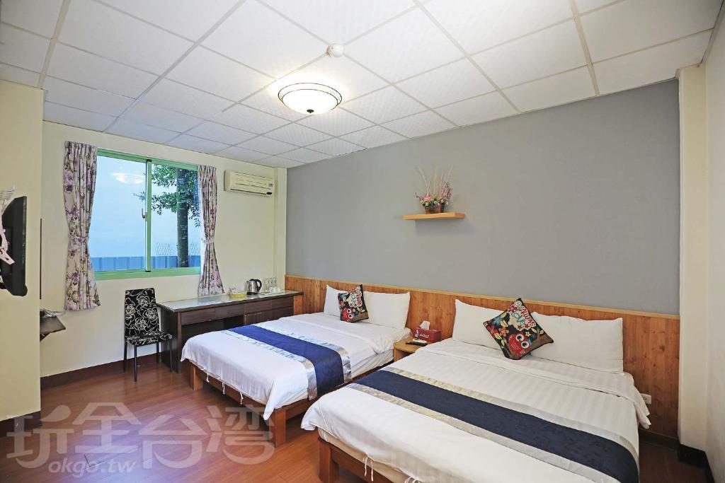 a bedroom with two beds and a desk and a window at Pulicity Villa B&amp;B in Puli