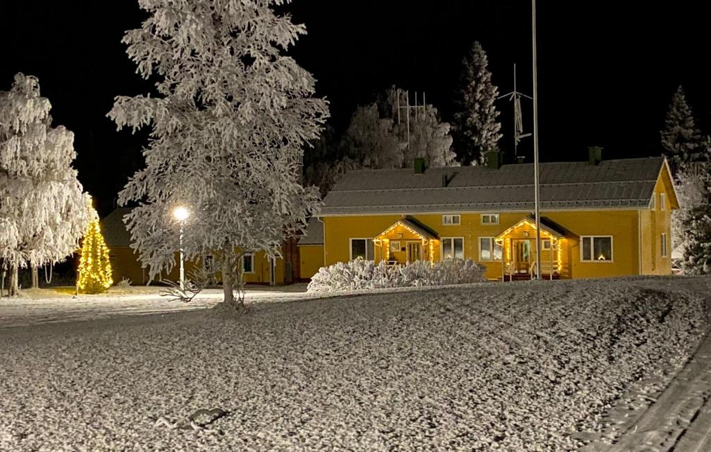 Wilderness Estate Pukari, Kuusamon Erämajoitus في كوسامو: منزل أصفر في الثلج في الليل