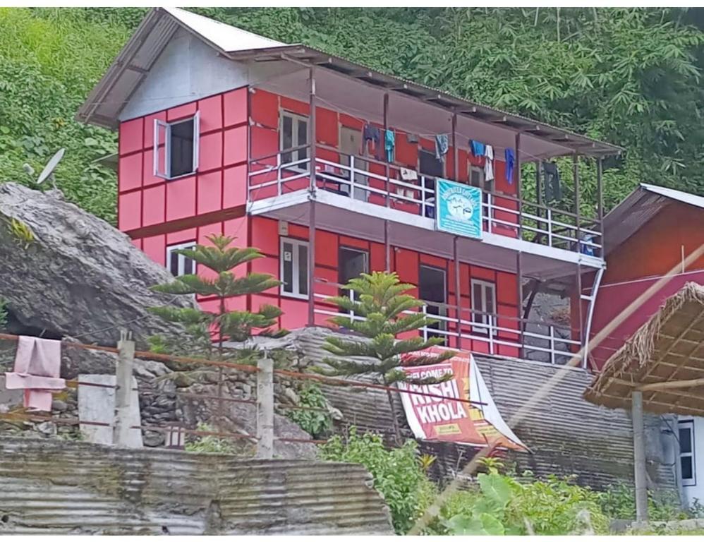 een rood huis met een balkon op een heuvel bij Rishi River Cottage, West Bengal in Pedong