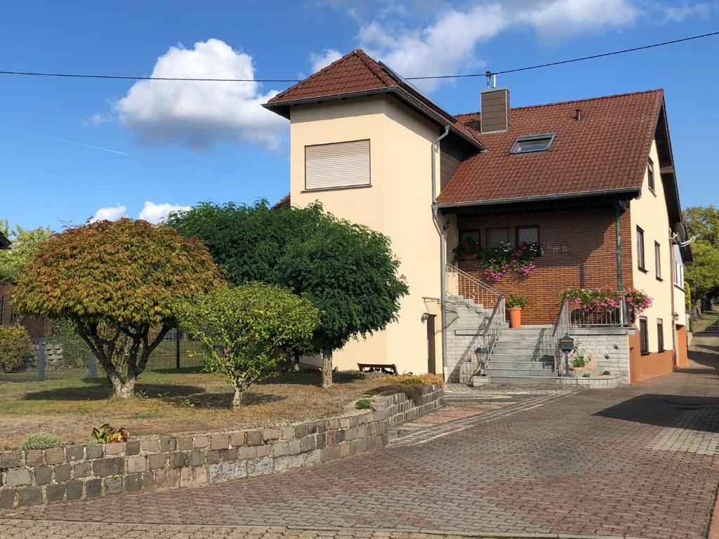 a white house with a brick street and trees at Rupp Ferienwohnung in Wallerfangen