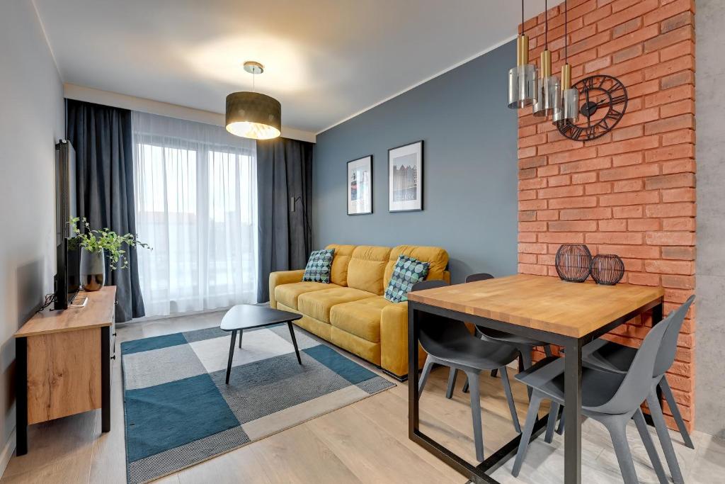 uma sala de estar com um sofá e uma mesa de jantar em Grano Residence Comfort Apartments em Gdansk