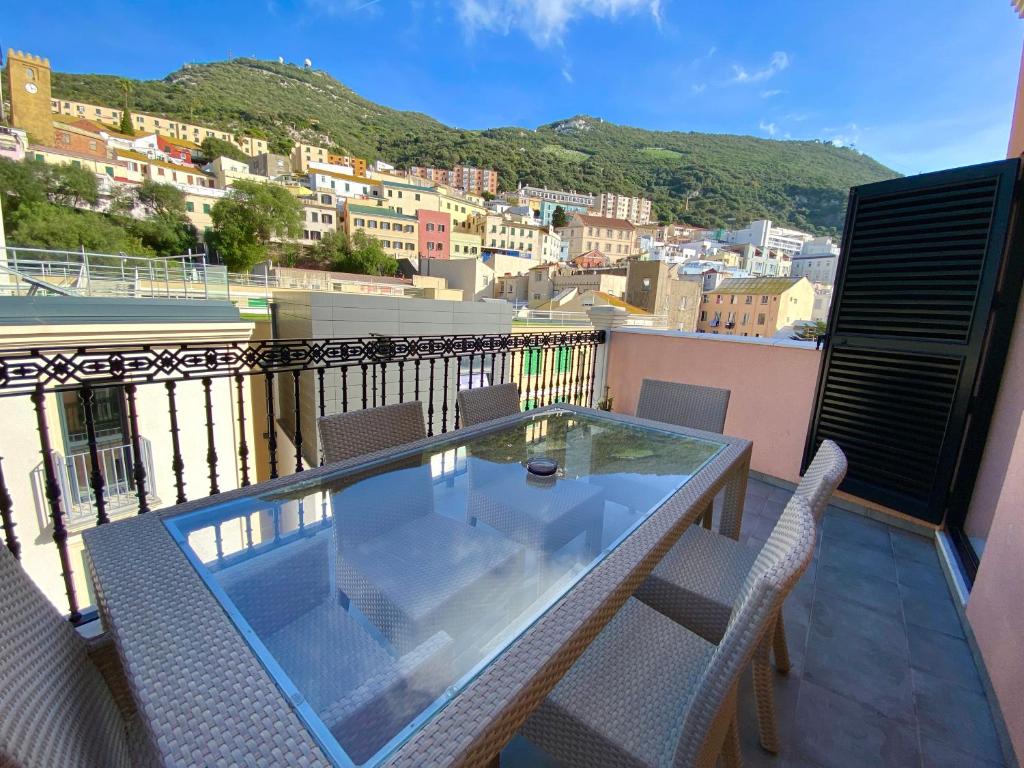 a balcony with a glass table and chairs on a balcony at Grand Central House - Luxe Penthouse Two Bedroom - GibraltarStay Apartments in Gibraltar