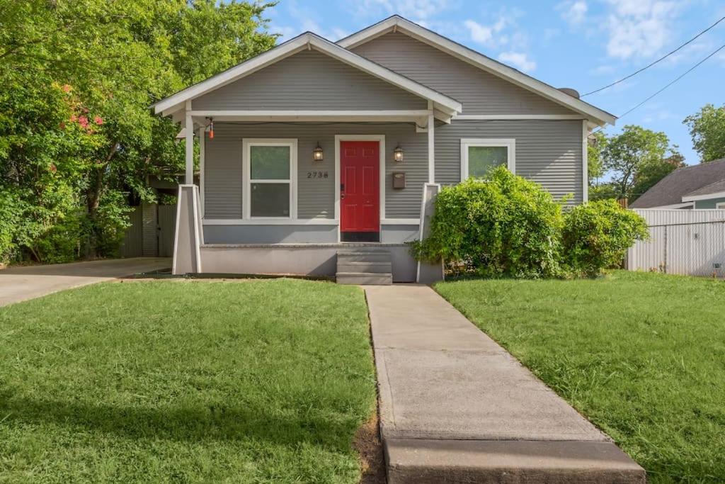 a house with a red door and a yard at Near Bishop Arts District Spacious 3 Bedroom Home! in Dallas