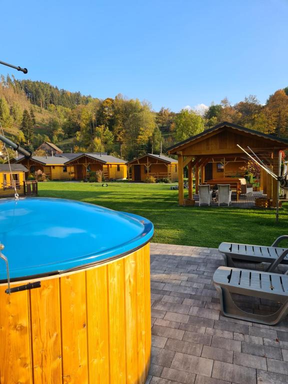 ein Pool mit zwei Bänken und ein Haus in der Unterkunft DOMKI POD ZIELONYM WZGÓRZEM in Kudowa-Zdrój