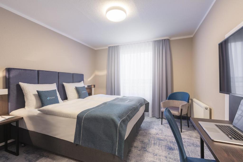 a hotel room with a bed and a desk and a laptop at Select Hotel Elmshorn in Elmshorn