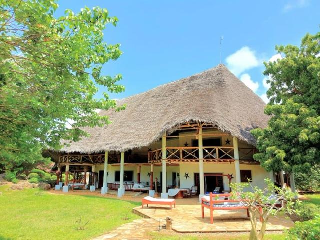 a large building with a thatched roof and a yard at Gulu House in Malindi