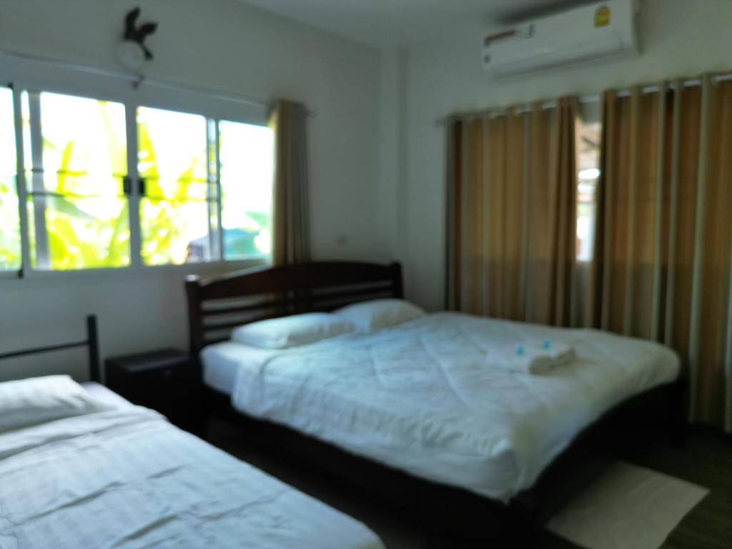 a bedroom with two beds and two windows at Open Kitchen in Chiang Rai