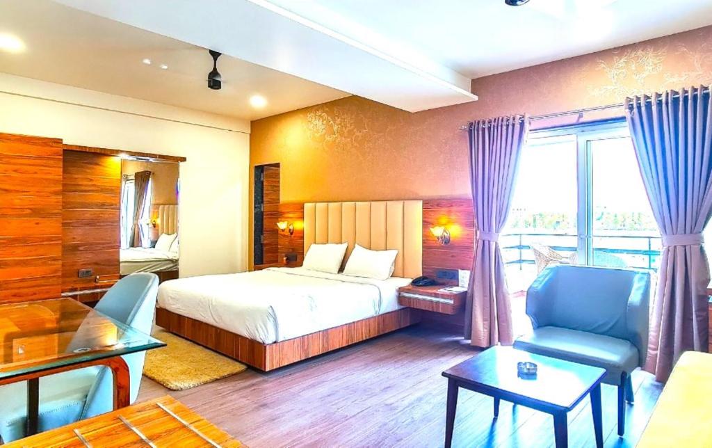 une chambre d'hôtel avec un lit, une table et des chaises dans l'établissement ROYAL CLIFF HOTEL & RESORTS, à Nagpur