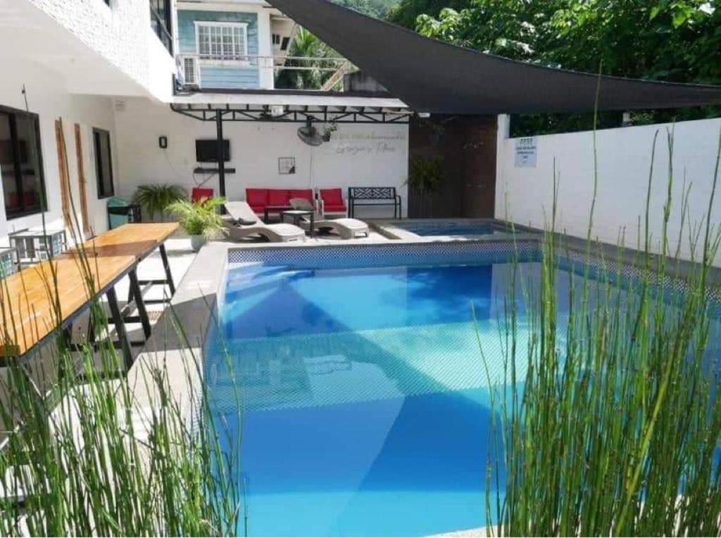 a swimming pool in a yard with tall grass at Felici's Private Resort in Los Baños