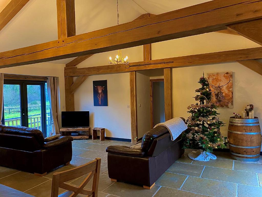 a living room with two couches and a christmas tree at Trelaske Mill Cider Barn-with Hot Tub, Fire Pit BBQ in Lewannick