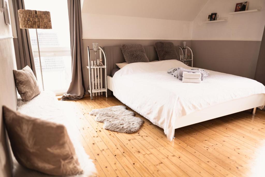 Schlafzimmer mit einem weißen Bett und Holzboden in der Unterkunft Pfälzer Herzel in Neustadt an der Weinstraße