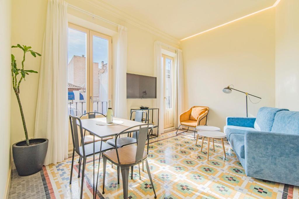een woonkamer met een blauwe bank en een tafel en stoelen bij Mosaiko Homes Catedral Granada in Granada