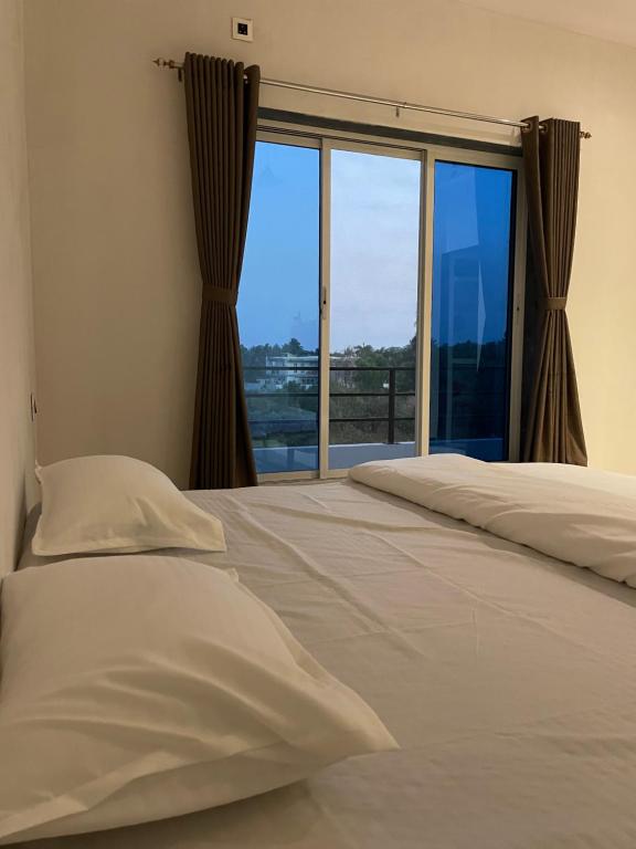 a bedroom with a bed and a large window at Scarlet Resort Alibag in Alibaug