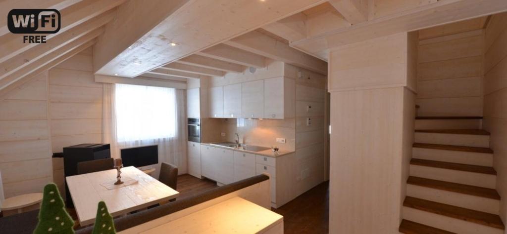 a kitchen with a table and a staircase in a room at Zoncolan Laugiane in Sùtrio