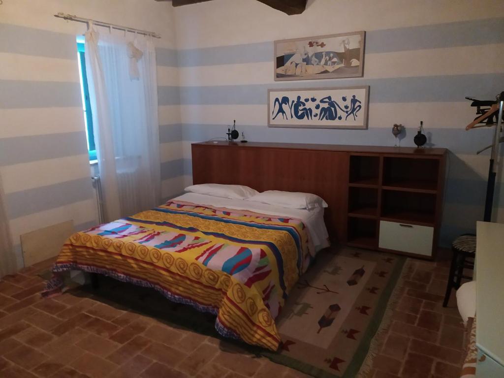 a bedroom with a bed with a striped wall at Agriturismo Paneolio in Villa Collemandina