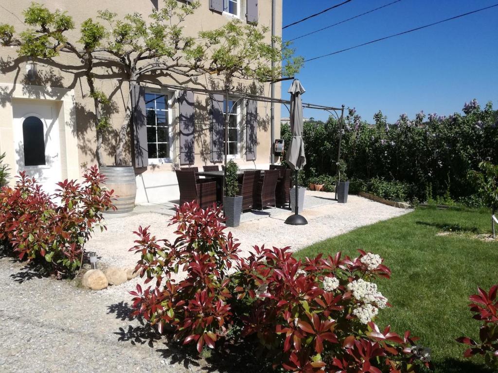 uma casa com um banco e flores em frente em Charme au cœur des vignes em Malras