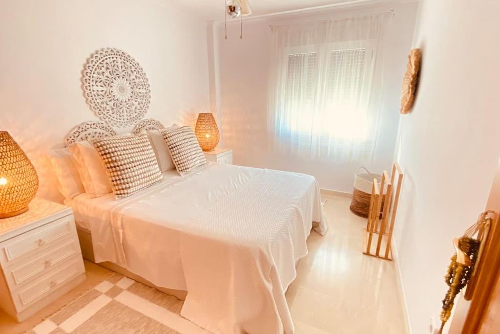 ein weißes Schlafzimmer mit einem Bett und einem Fenster in der Unterkunft Beach Penthouse Apartment in Jávea