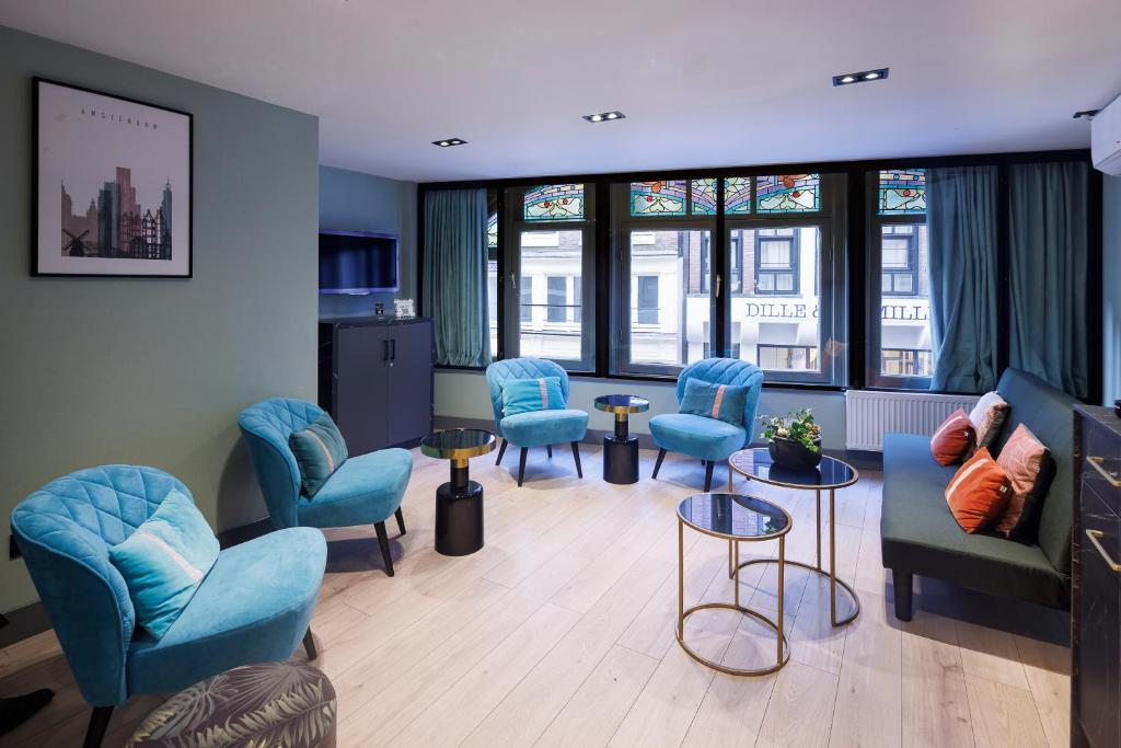 a waiting room with blue chairs and tables and windows at Ciao Papa Hotel Amsterdam Central Station in Amsterdam
