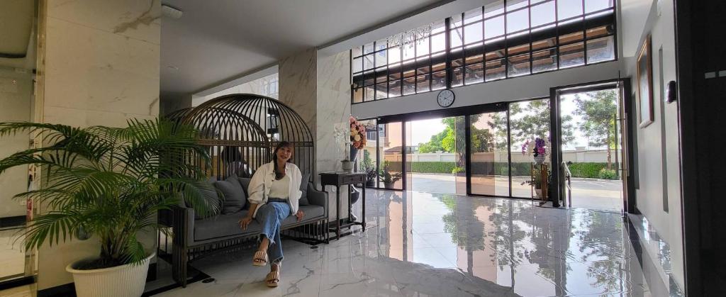 une femme assise dans une cage pour oiseaux dans un bâtiment dans l'établissement Baan Thanakul Residences, à Samutprakarn