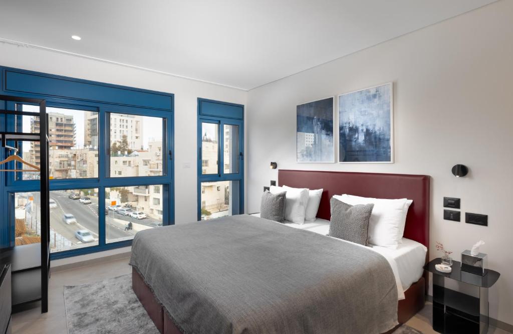 a bedroom with a large bed and large windows at AMALON Boutique Apartments in Jerusalem
