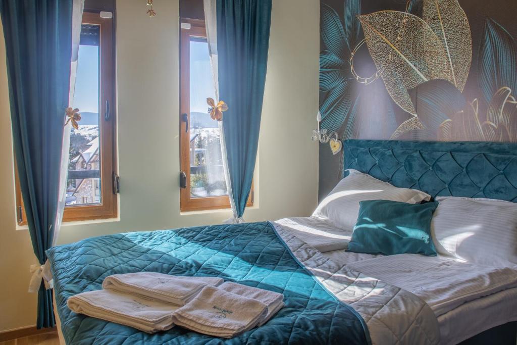 Un dormitorio con una cama azul con toallas. en Apartman Morska Pahulja Zlatibor i spa centar, en Zlatibor