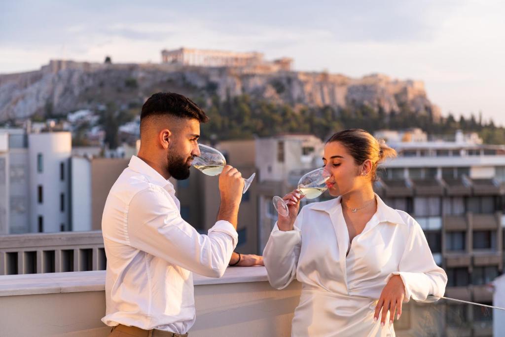 um homem e uma mulher a beber vinho numa varanda em Enattica Suites em Atenas