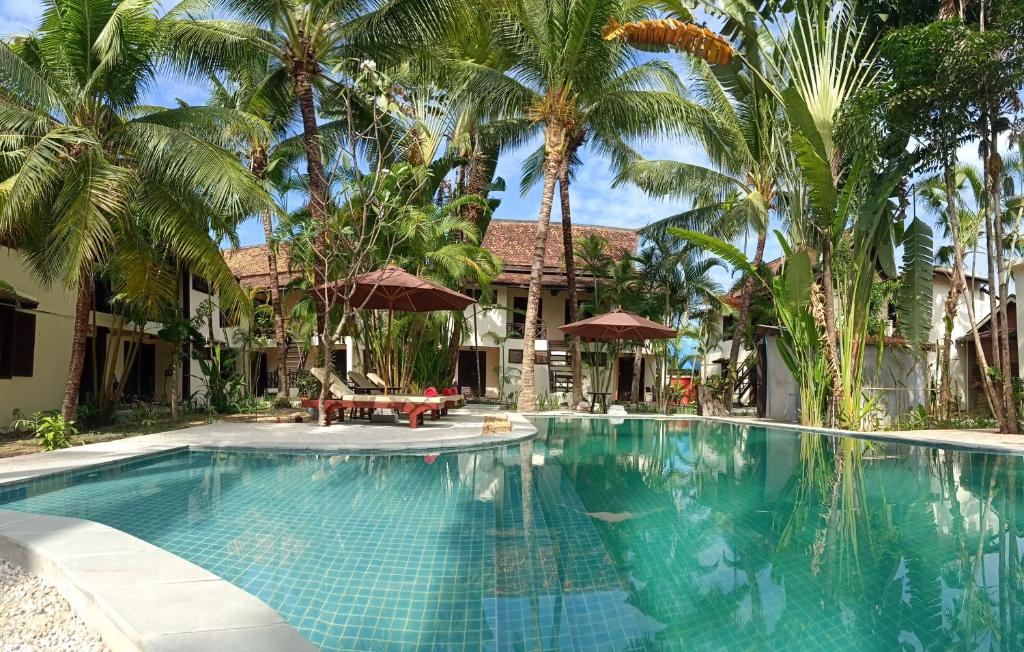 a swimming pool in front of a house with palm trees at Natural Relax Villa in Siem Reap