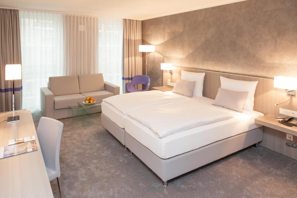 a bedroom with a large white bed and a couch at relexa hotel München in Munich