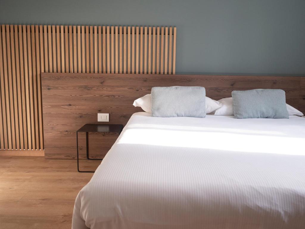 una camera da letto con un grande letto bianco con due cuscini di Innesti Rooms&Apartments a Pergine Valsugana